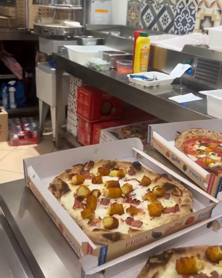 Il laboratorio: pizze appena sfornate nei cartoni, pronte a partire, e le piastrelle alle pareti