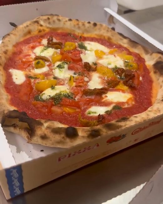 Una pizza rossa con pomodorini gialli appena sfornata